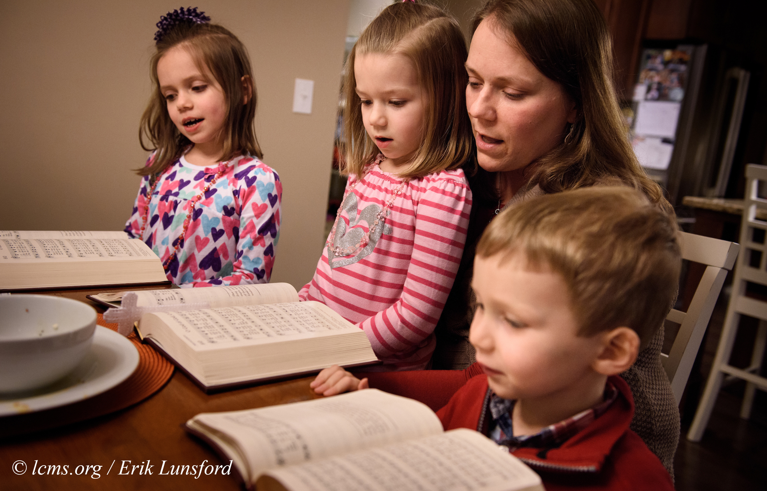 Laurie Vogt sings from the Lutheran Service Book with her children Elizabeth, Abigail (in lap) and Carl during an evening devotion with the Congregation at Prayer resource at their home on Sunday, Feb. 7, 2016, in Menomonee Falls, Wis. LCMS Communications/Erik M. Lunsford
