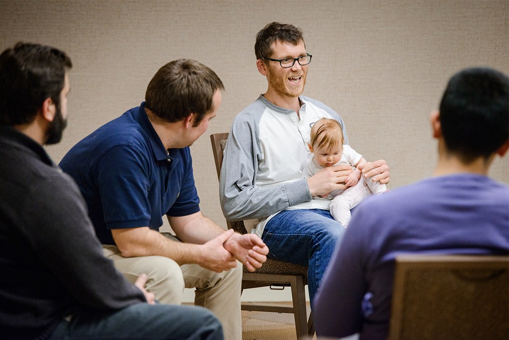 Members of Rev. Andy and Nikki Becker’s PALS group discuss their ministries Jan. 5 in St. Louis. From left are Revs. Michael Dobler, Daniel Maske, Jacob Hercamp (holding his daughter, Ella) and “AJ” Espinosa. (LCMS/Erik M. Lunsford)