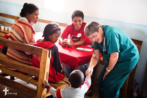 LaDonna Smith greets a new patient at the Mercy Medical Team clinic on Saturday, Oct. 18, 2014, at a Fiangonana Loterana Malagasy (FLM) Lutheran church in Antsoantany, Madagascar. Behind LaDonna is Solomona John Rakotonirina. LCMS Communications/Erik M. Lunsford