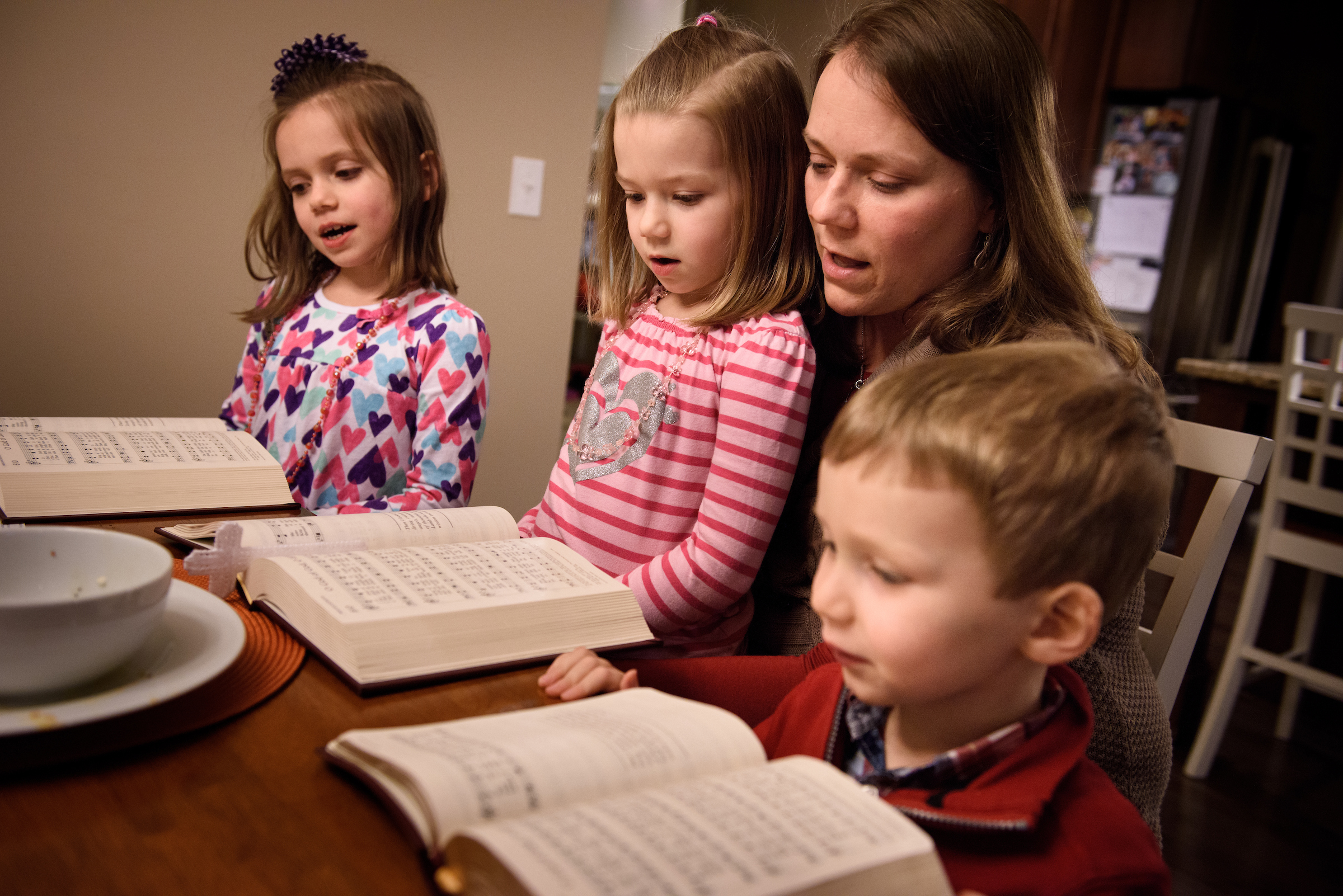 Laurie Vogt sings from the Lutheran Service Book with her children Elizabeth, Abigail (in lap) and Carl during an evening devotion with the Congregation at Prayer resource at their home on Sunday, Feb. 7, 2016, in Menomonee Falls, Wis. LCMS Communications/Erik M. Lunsford
