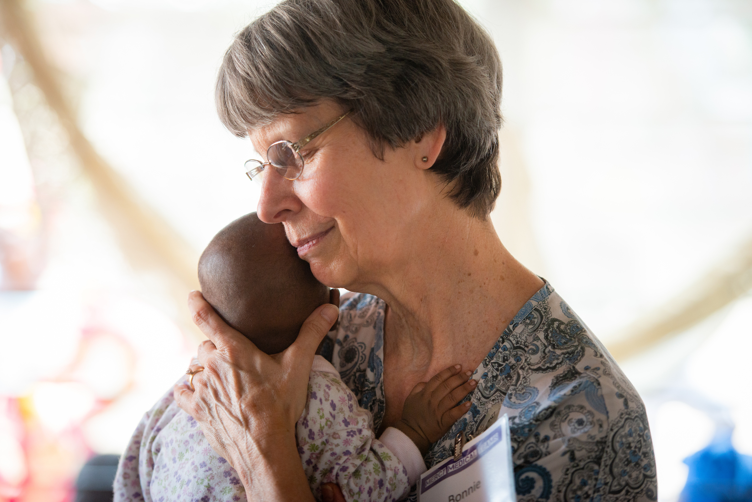 Bonnie Hartman, a member of Faith Lutheran Church, Godfrey, Ill., spends a few joyful moments holding an infant on the third day of the LCMS Mercy Medical Team on Wednesday, May 9, 2018, in the Yardu village outside Koidu, Sierra Leone, West Africa. LCMS Communications/Erik M. Lunsford